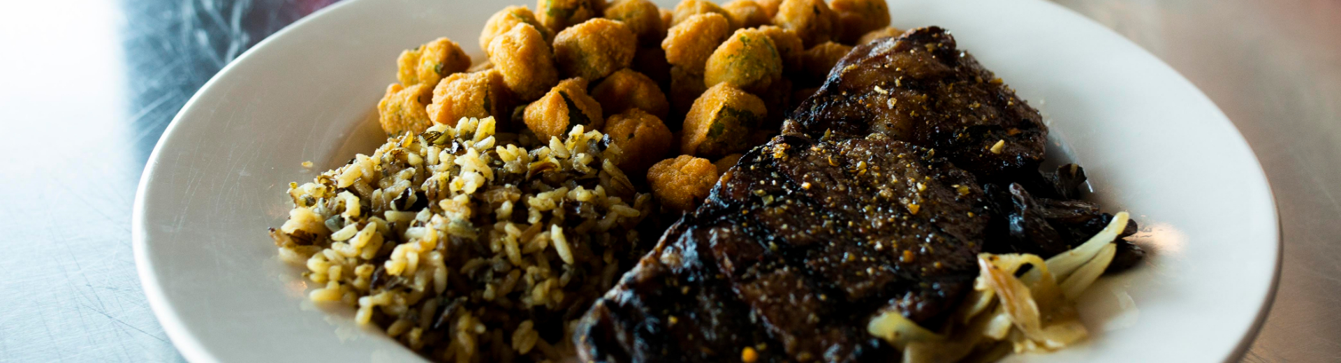A plate of steak, rice and fried okra, prepared by House Divided